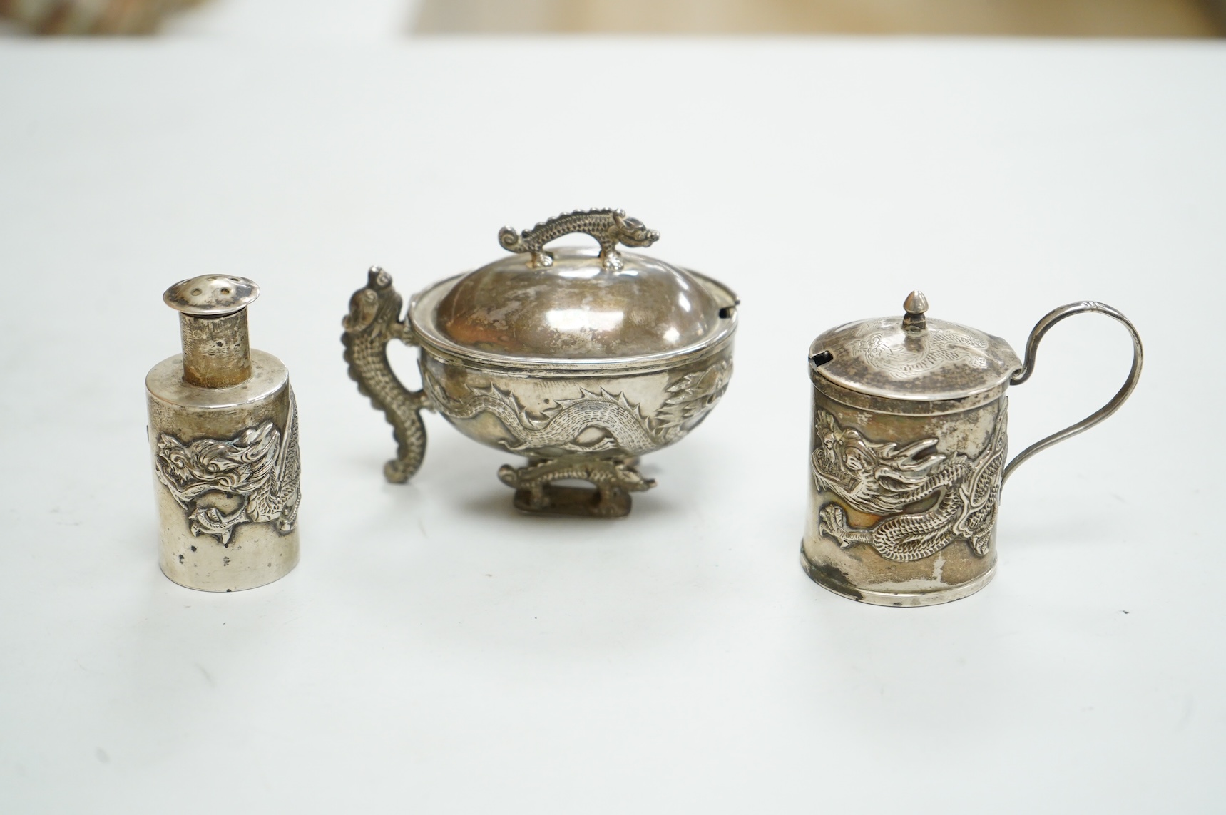 Three early 20th century Chinese export white metal condiments including a drum mustard pot and pepperette by Wang Hing, Hong Kong, pepperette 63mm.